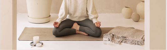 Person meditating crossed legs on a yoga matt with a Shō-moon meditation candle