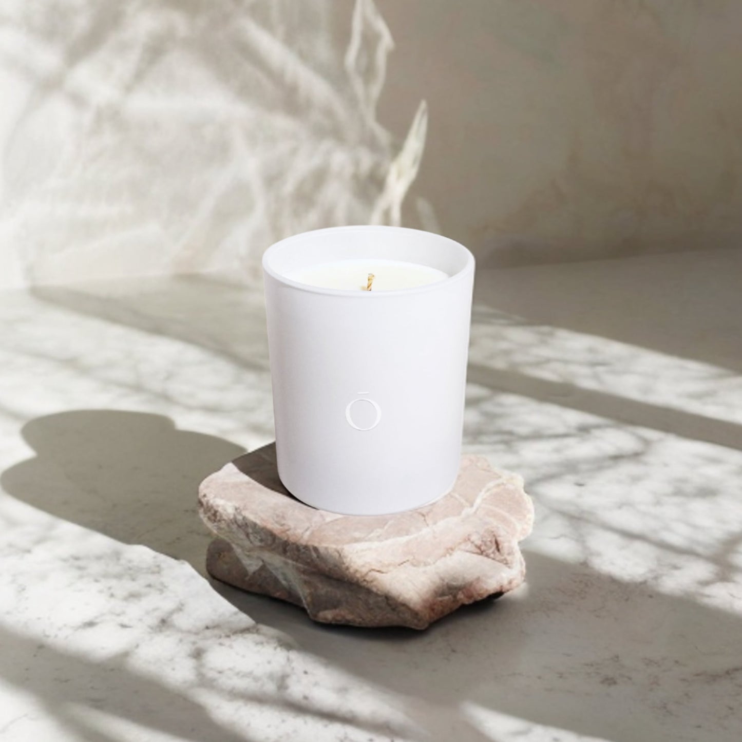 Shō-moon Energise Meditation Candle on top of a rock and Marple surface with soft shadows