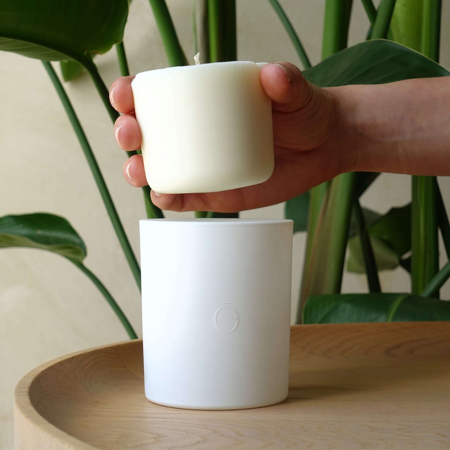 Hand holding shō-moon candle refill above candle jar