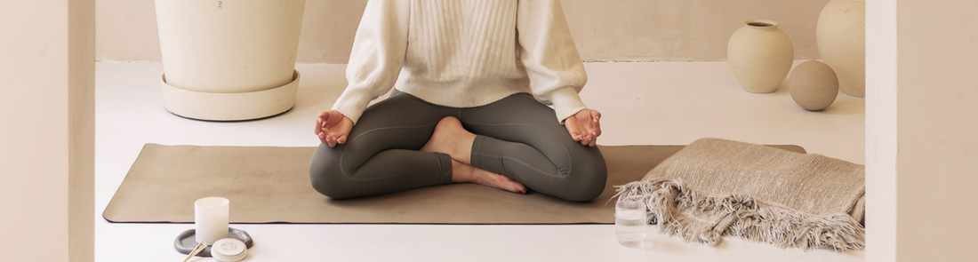 Person meditating crossed legs on a yoga matt with a Shō-moon meditation candle
