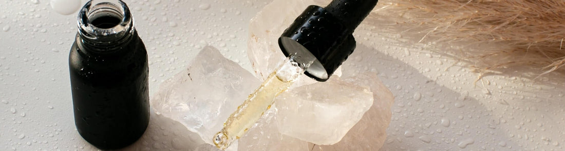 Essential oil bottle and pipette on top of clear quartz