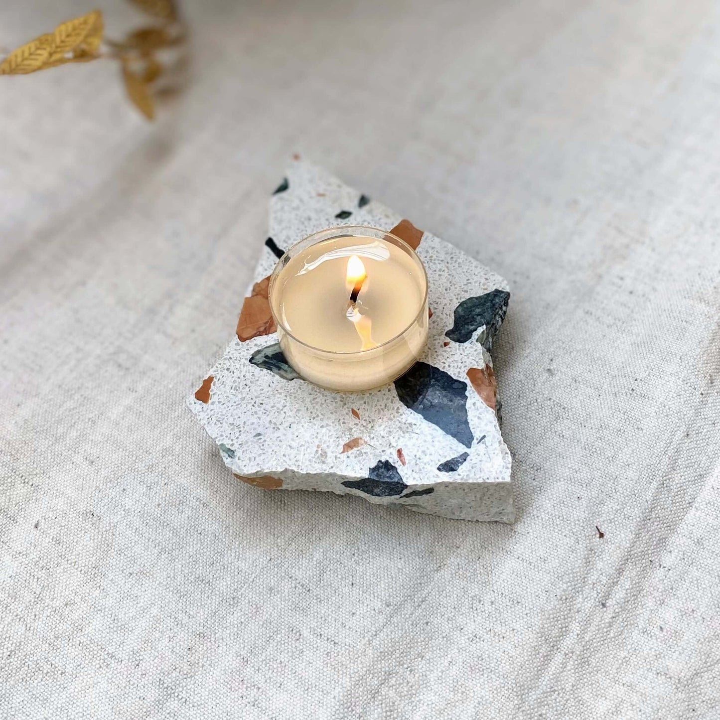 Shō-moon Natural and refillable Energise scented Tealights lite up on a piece of Terrazzo