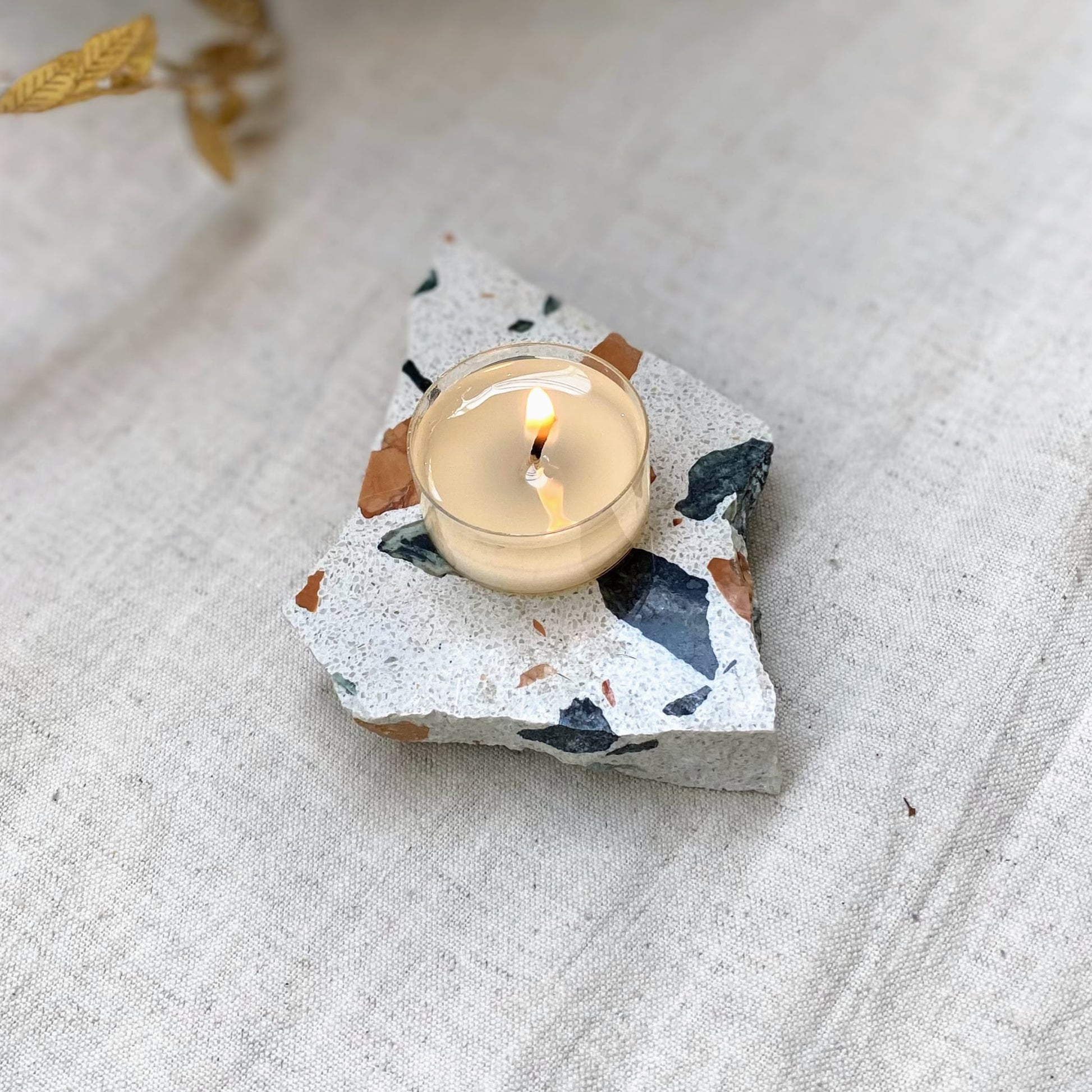 Shō-moon Natural and refillable Energise scented Tealights lite up on a piece of Terrazzo