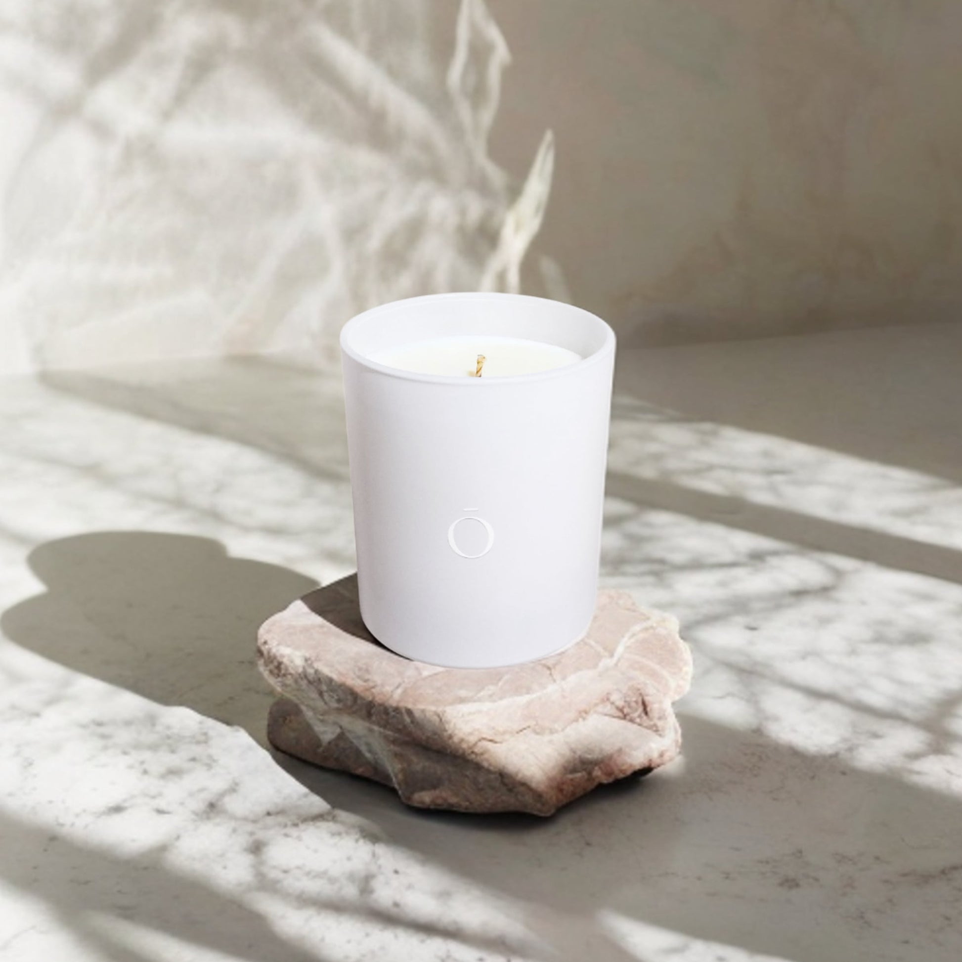 Shō-moon Energise Meditation Candle on top of a rock and Marple surface with soft shadows 